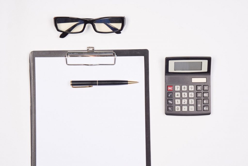 Prancheta, caneta, óculos e calculadora