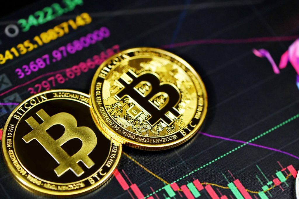 Duas moedas de bitcoin com gráficos de exchange no fundo