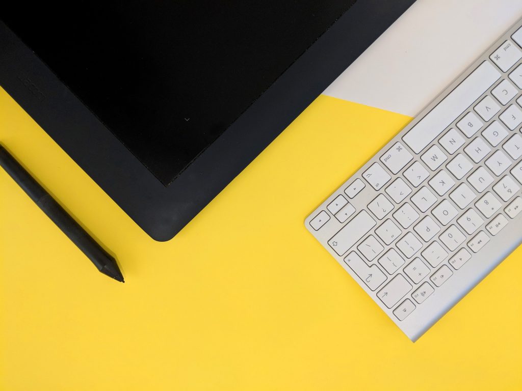 Tablet, caneta, papel e teclado de computador, representando formas de solicitar o crédito Santander