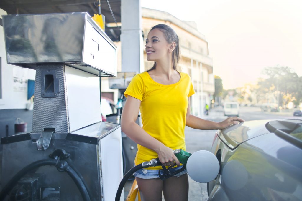 pessoa de blusa amarela abastecendo o carro no posto de combustível