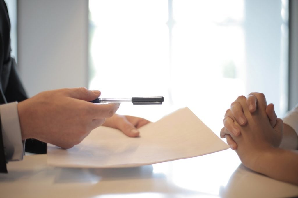 imagem com duas pessoas com um mapa de responsabilidades de crédito sob uma mese com uma caneta na mão para sua assinaturaa