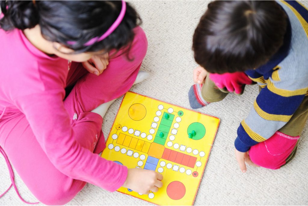 duas crianças brincando de um jogo de tabuleiro