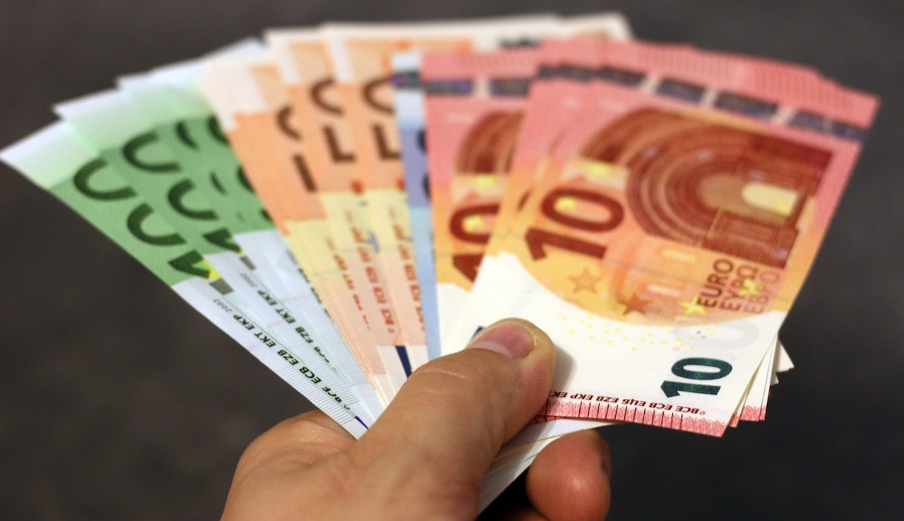 mão segurando notas de 10, 50 e 100 euros