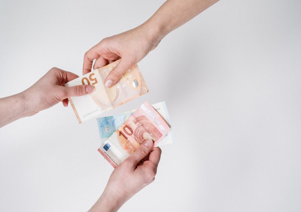 duas mãos trocando notas de euros