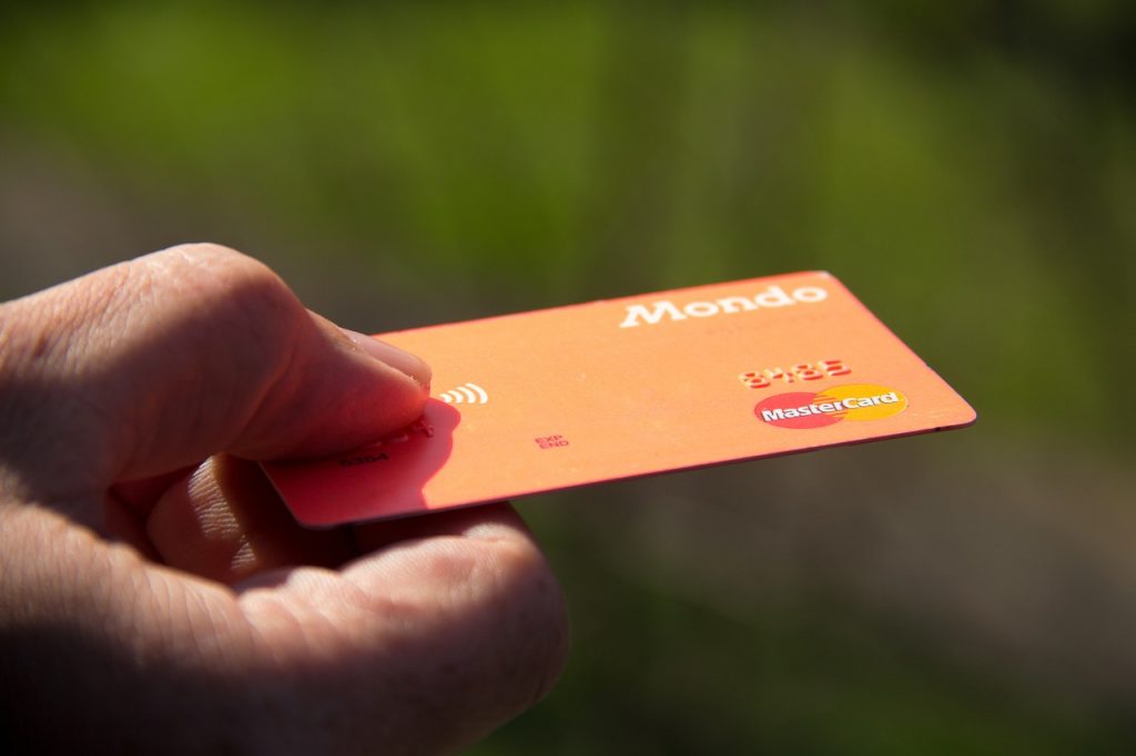 Mão entregando cartão laranja Mastercard