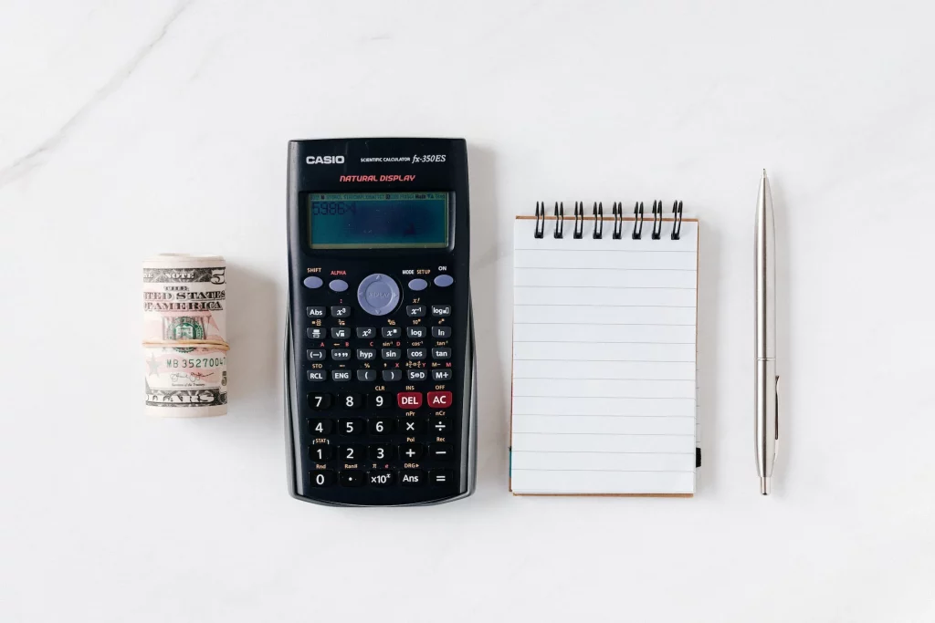 Rolo de dinheiro, calculadora e caderneta