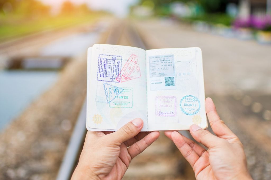 Mãos segurando passaporte aberto com carimbos