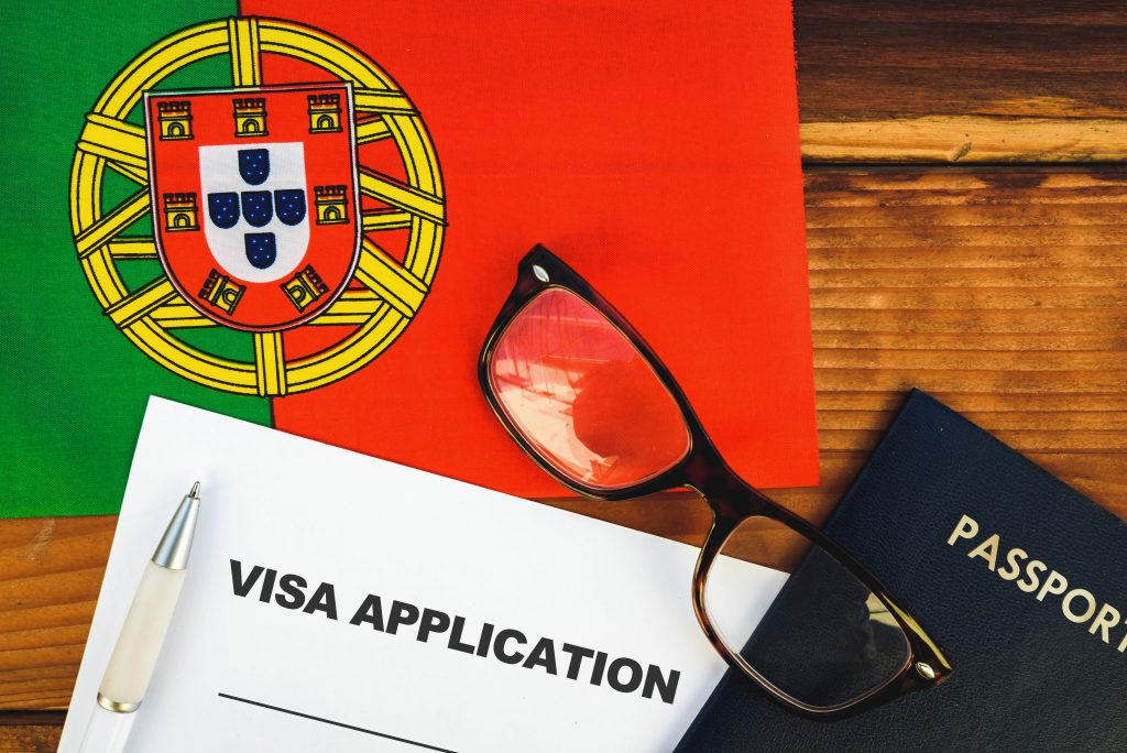 Óculos e formulário de visto sobre mesa com bandeira de Portugal
