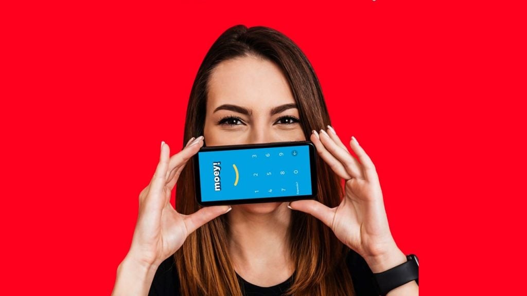Mulher segurando celular com app moey! na frente da boca