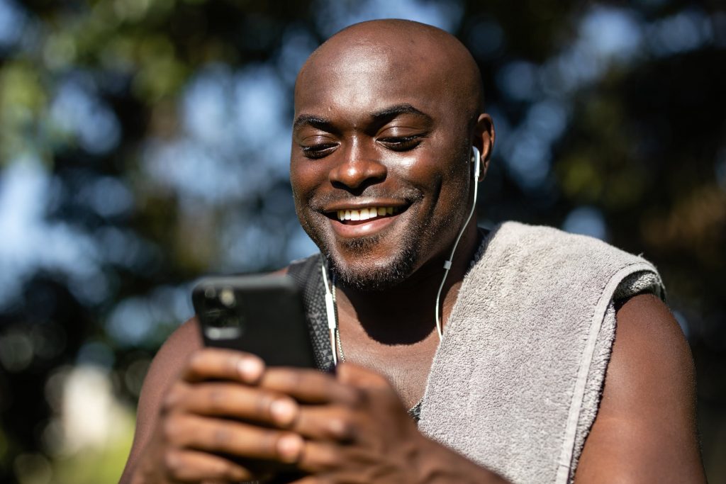 Homem esportista usando celular e sorrindo