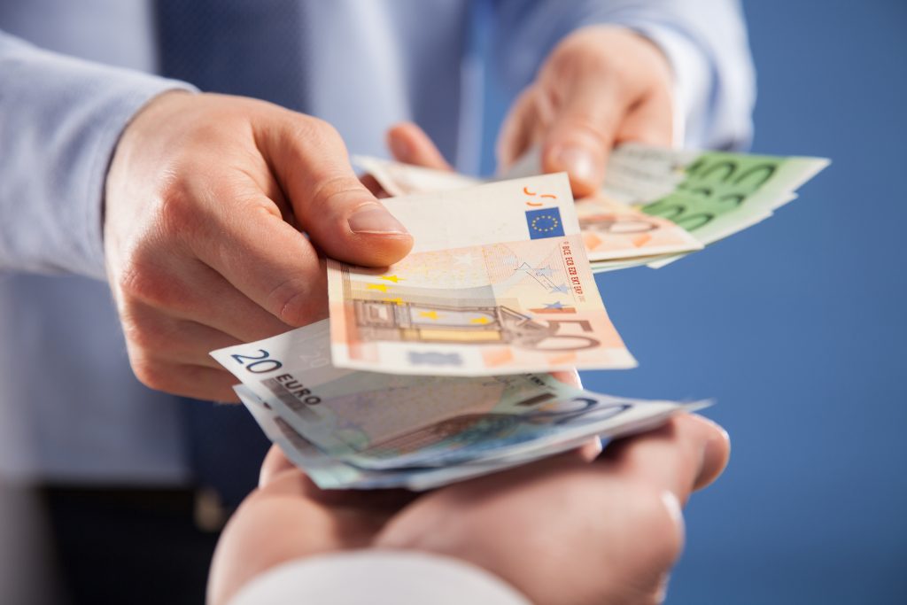 Mão entregando notas de euro para outra mão