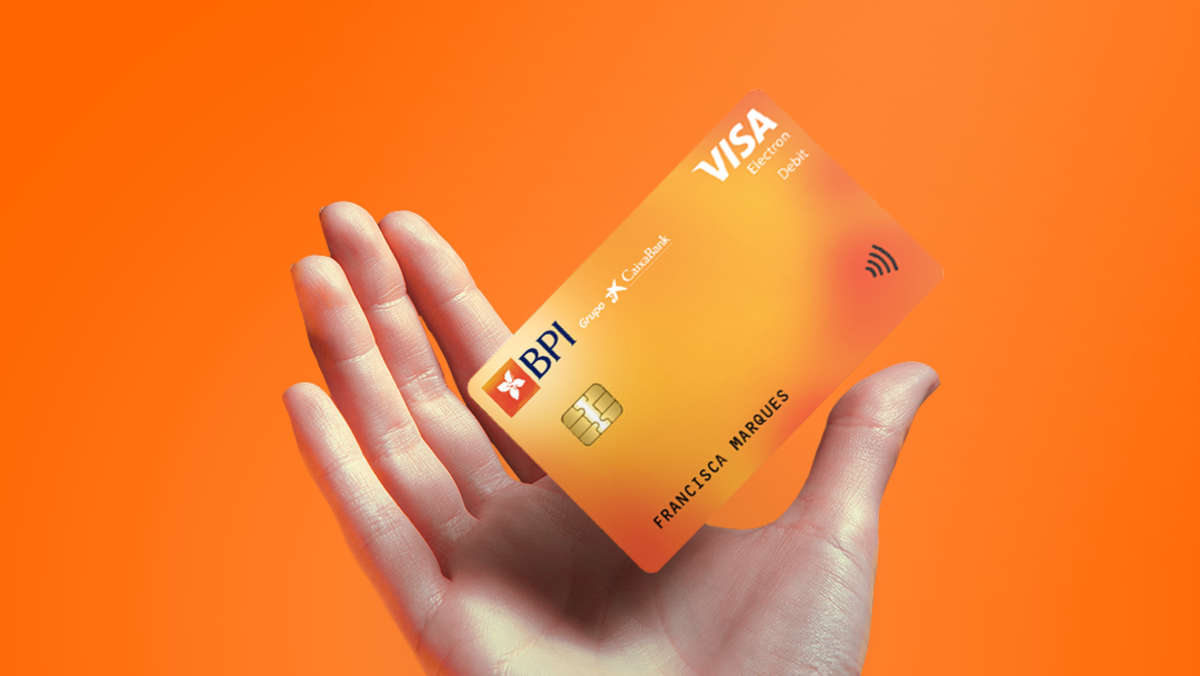 Mão com cartão de débito BPI Electron fundo laranja