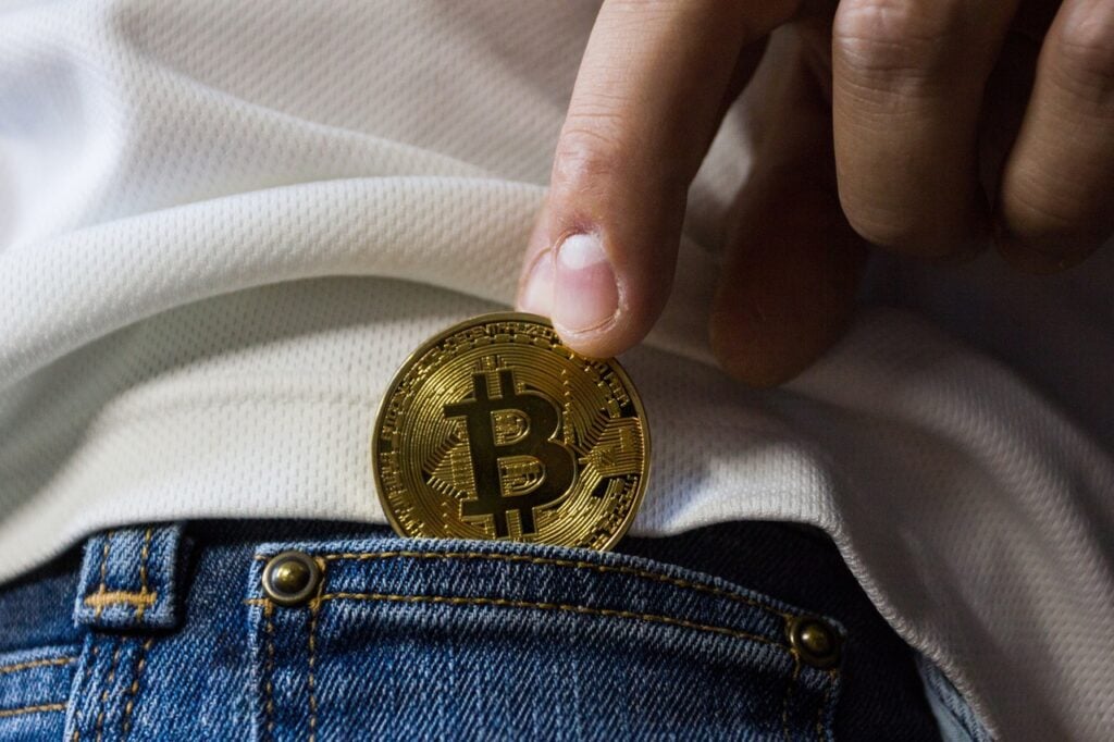 Pessoa colocando bitcoin no bolso