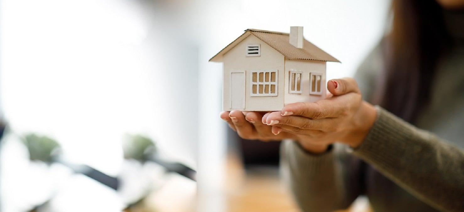 pessoa segurando casa (habitação) em miniatura na mão