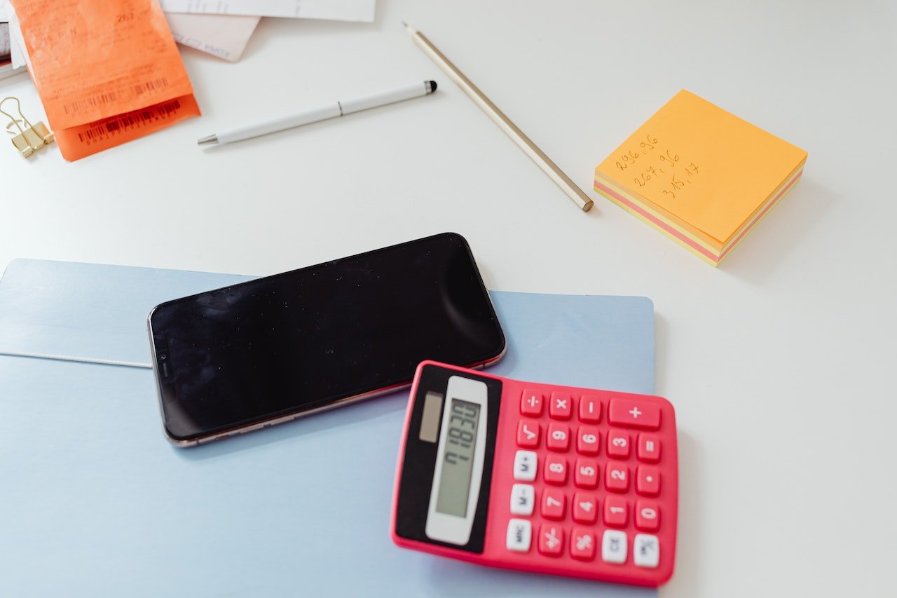 calculadora, celular e alguns papéis sobre a mesa