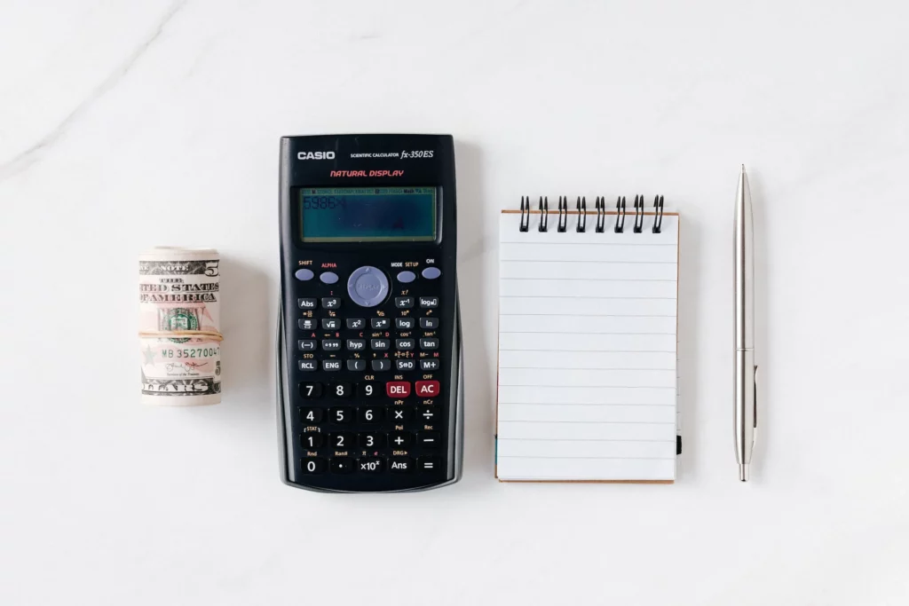 Rolo de dinheiro, calculadora e caderneta