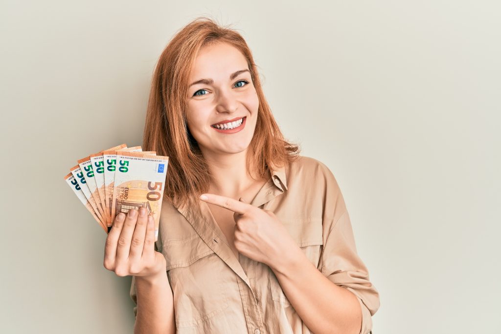 Mulher sorrindo apontando para dinheiro nas mãos
